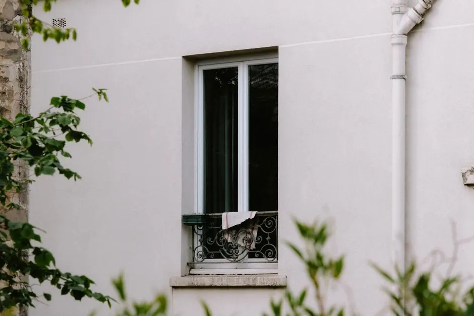 A window with decorative grill and cloth on a residential building wall.